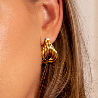 Close-up view of the Aphrodite Coil Earrings showcasing the layered gold coil design on the ear.