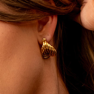 Side profile image featuring the Aphrodite Coil Earrings worn on the ear, highlighting the sculptural gold coils.