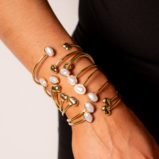 Model wearing multiple Athena Pearl Bangles in gold, stacked on the wrist with imitation pearls.