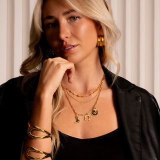 Model wearing triple gold hoop earrings styled with layered gold necklaces and black leather jacket, Nashville Collection look.