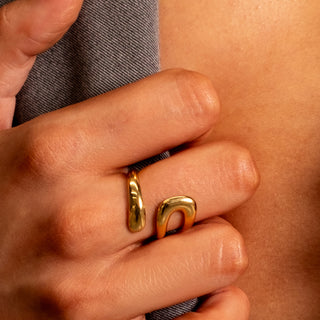 Close-up of the Emily Twist Ring in polished 18k gold, featuring a fluid sculptural open-twist design, worn on the finger for a modern minimalist yet bold look.
