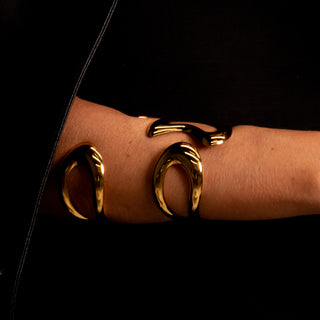 Side angle of the Hannah Cuff Bracelet in 18k gold highlighting fluid, curved statement structure against black outfit