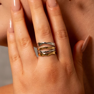 Close-up of the two-toned Manhattan Liquid Ring on a model’s hand, showing its fluid, wave-like gold and silver design.