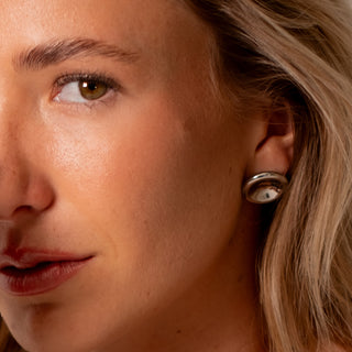 Model wearing silver dome earrings, highlighting their high-shine, rounded silhouette from the Silver Wolf Collection.