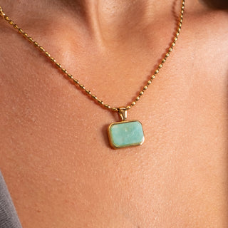 Close-up of the Serena Amazonite Necklace featuring a natural rectangular amazonite stone in a polished gold setting on a beaded chain.