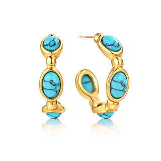 Gold hoop earrings featuring three vivid turquoise oval stones with natural veining, set in polished gold bezels. The hoops have a smooth, sculptural shape and a glossy, high-end finish against a white background.