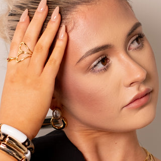 Cara Pearl Twist Hoops gold pearl hoop earrings styled with gold rings and bracelets