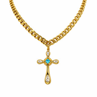 Gold chunky chain necklace featuring a cross pendant with pear-cut clear stones and a central blue gemstone, photographed on a plain background. A bold statement piece from Forward & Tame inspired by modern European luxury.